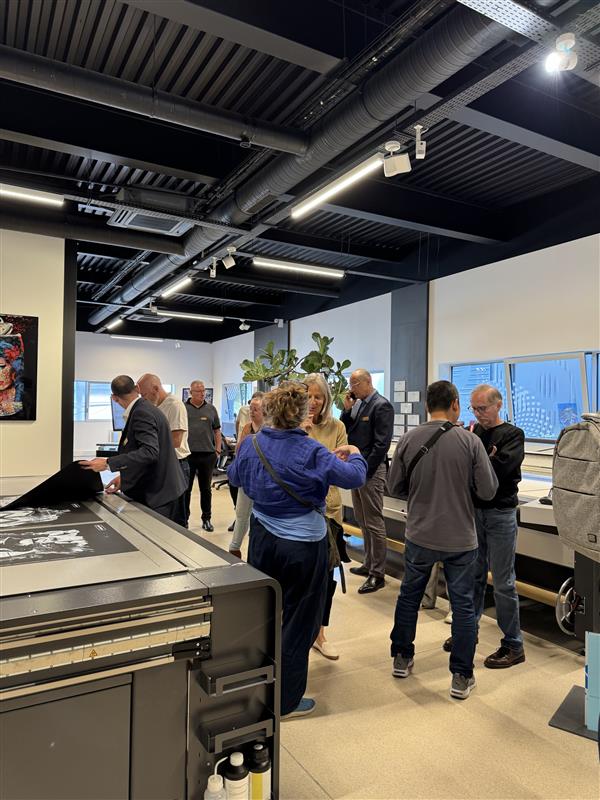 Groupe de visiteurs autour d’une impression en sortie de machine